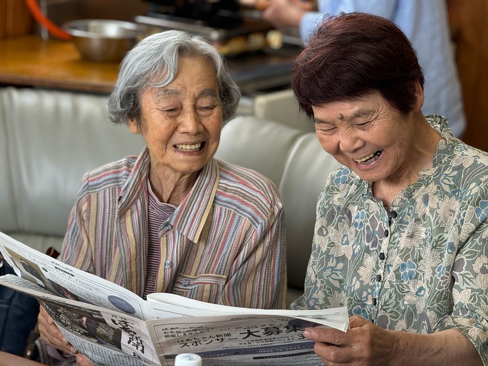 新聞を読んで談笑している様子（うきはの宝さんより提供）