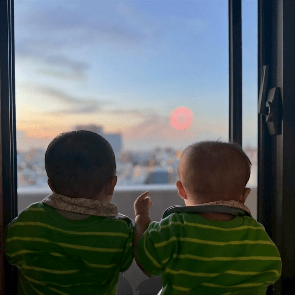 窓から外を眺める2人（＠ochacha.twinsさんより提供）