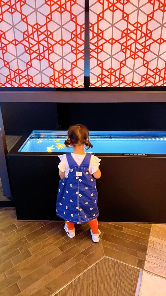 水族館で金魚に釘付けの娘さん①（＠morico_moさんより提供）