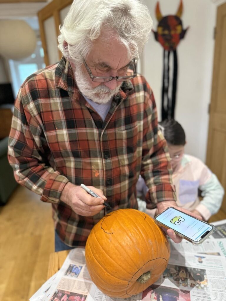 スマートフォンでキャラクターを見ながら下絵を描くおじいちゃん（＠mieko.kosodateさんより提供）