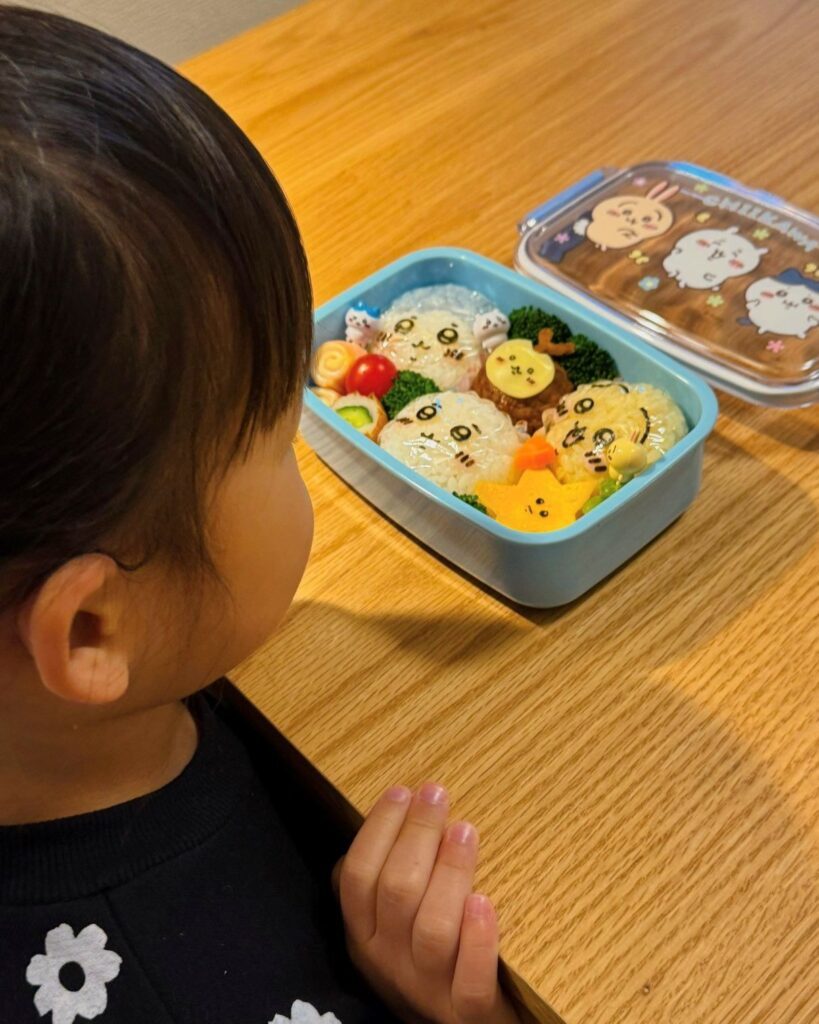 お弁当を見つめる娘さん（＠kuronushi_さんより提供）